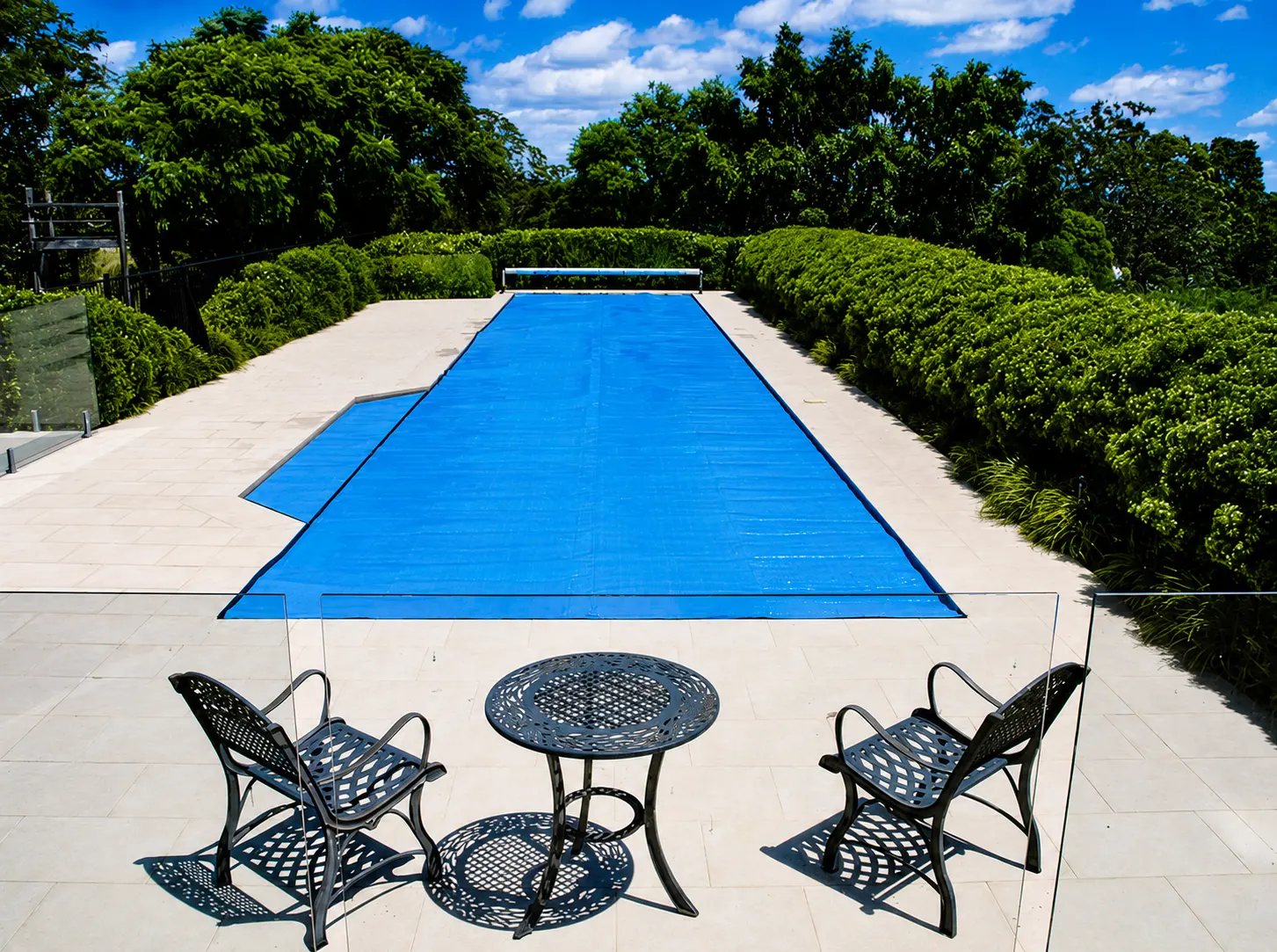 Blue rectangular pool cover in a backyard